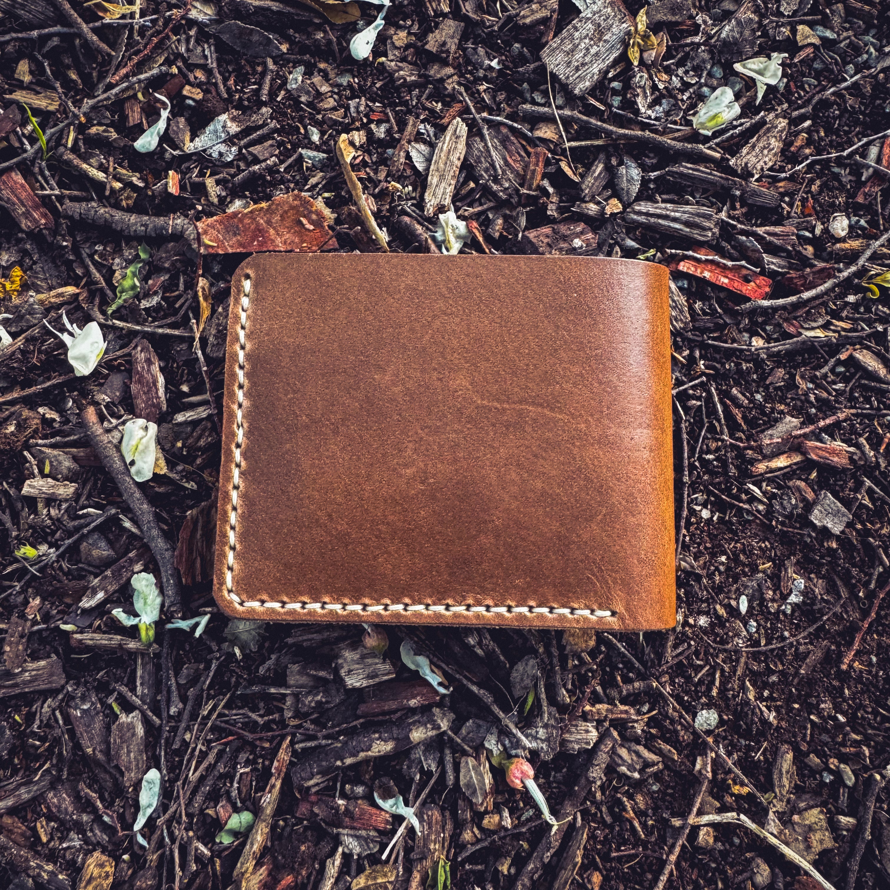 No. 2 Frontiersman Leather Bifold Wallet, Horween Natural Chromexcel Leather, Inside Closed Back laying on rugged ground