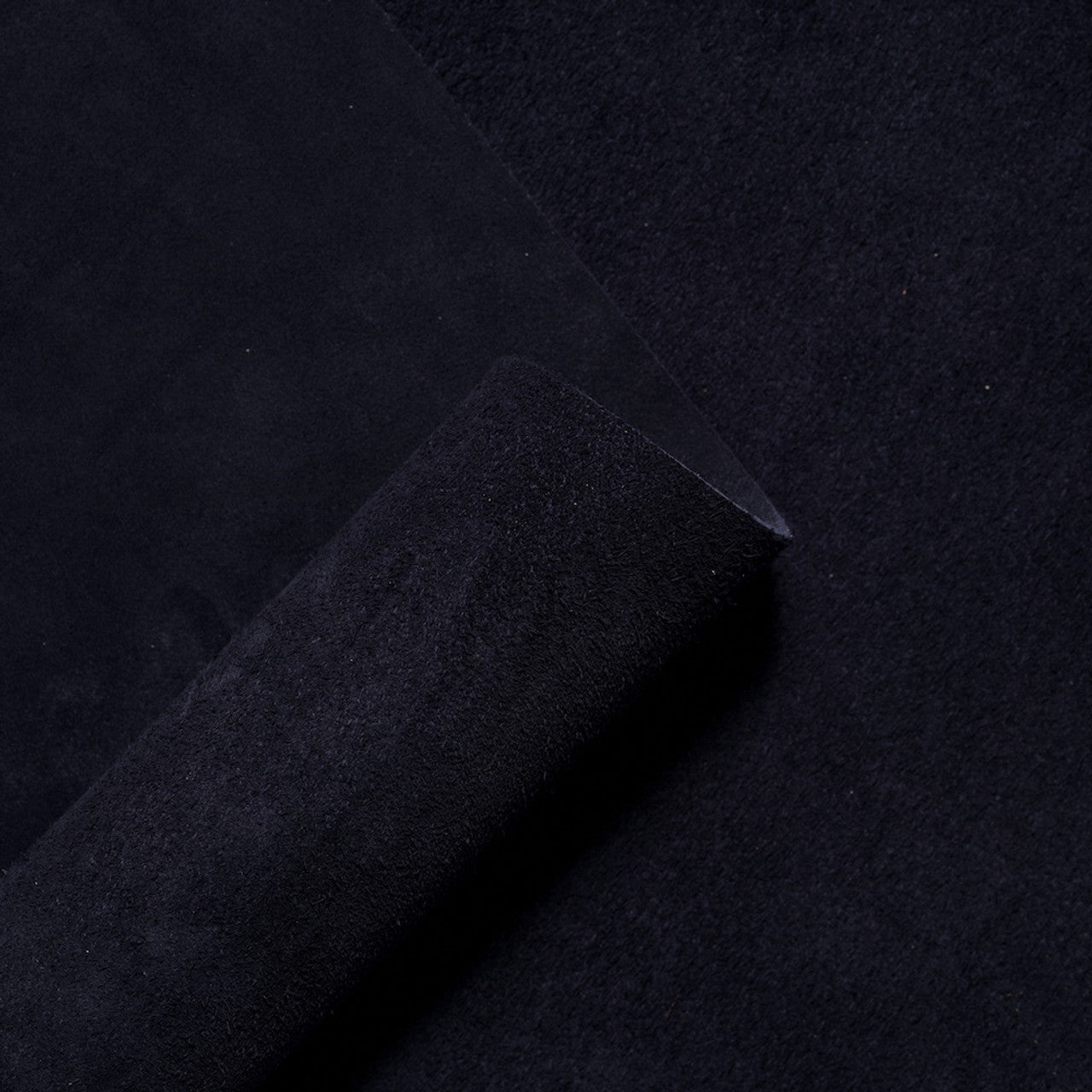 Rolled suede leather hide in a classic navy blue, highlighting the soft velvety nap and luxurious texture of premium Italian suede from Opera Conceria.