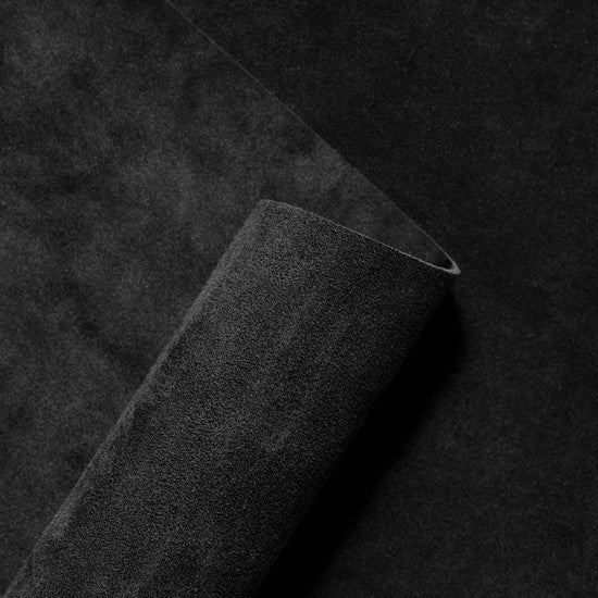 Rolled suede leather hide in deep Nero black, showcasing the soft velvety nap and rich texture of premium Italian suede from Opera Conceria.