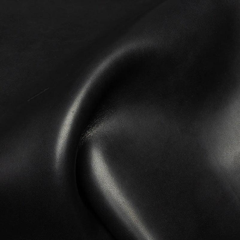 Detailed macro texture shot highlighting the deep black tones and characteristic grain structure of premium Horween Dublin leather.