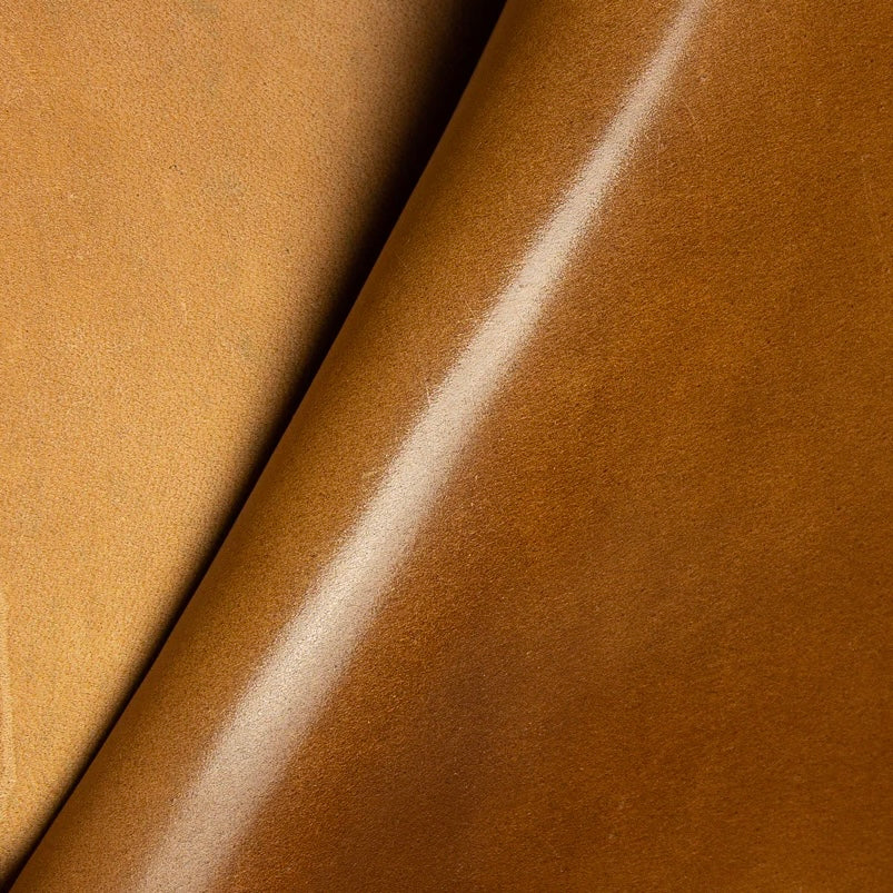 Detailed macro texture shot highlighting the warm, golden-brown Bourbon tones and smooth, dense grain of premium Horween Shell Cordovan leather.