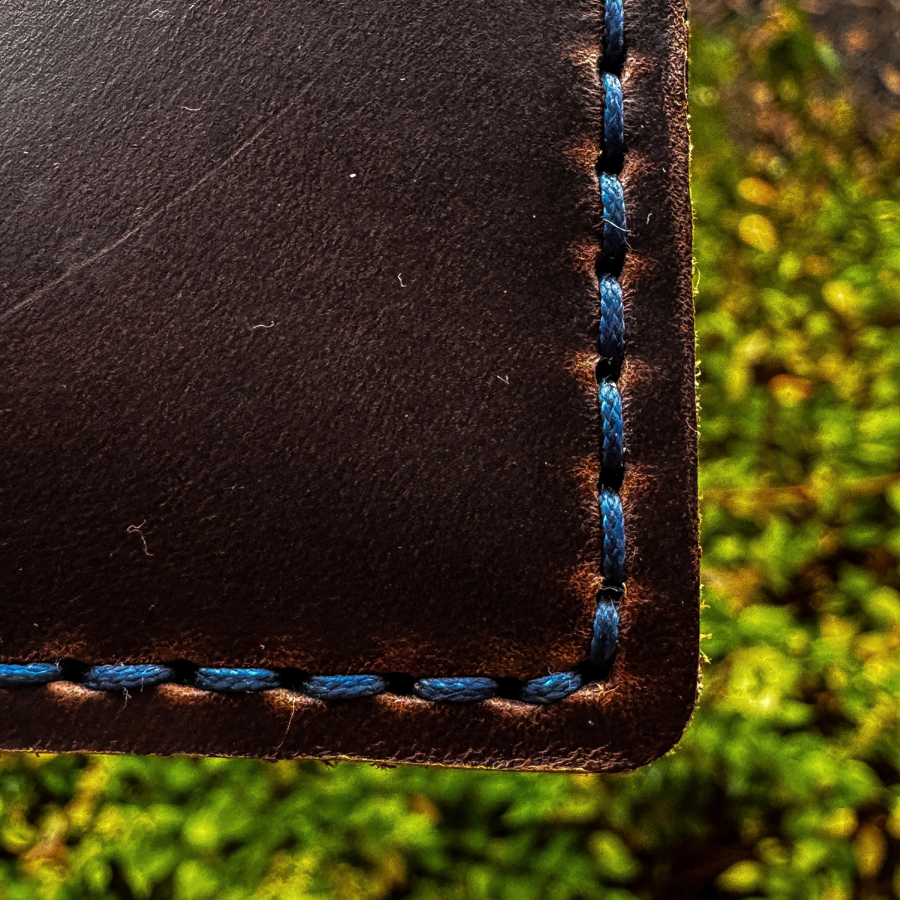 Extreme close-up of the custom blue hand-stitching and burnished edge on the corner of the No. 2 Frontiersman Leather Bifold Wallet, handcrafted from Brown Chromexcel.