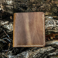 The closed exterior view of the No. 3 Pioneer Billfold Coin Wallet crafted from Natural Horween Chromexcel leather. The image highlights the smooth finish, rich pull-up color variations, and precise contrast hand-stitching along the edges, set against a rugged tree bark background.