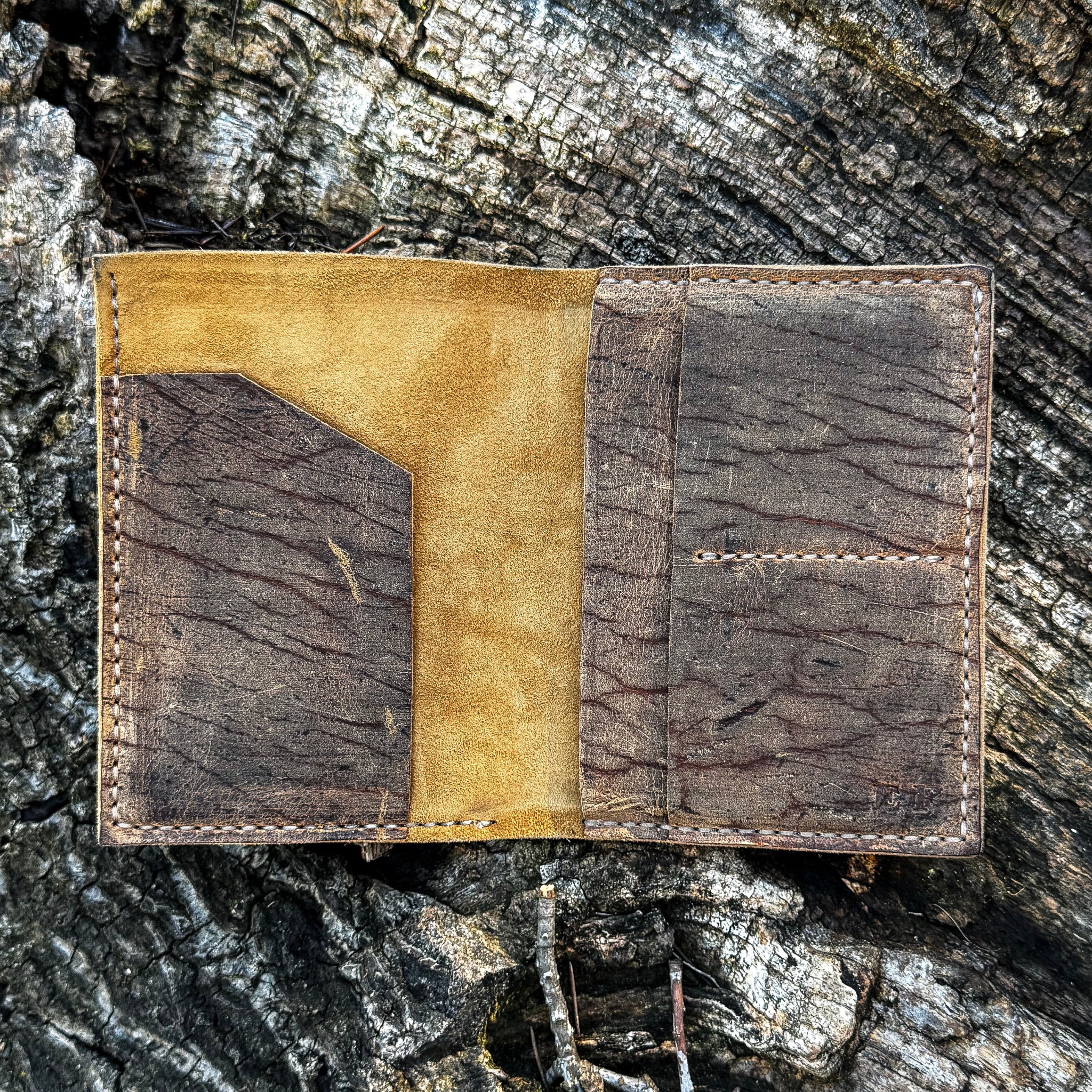 The interior view of the open No. 4 Journeyman Passport Wallet laid flat, crafted from Baobab Wild African Kudu leather. The image highlights the contrasting soft golden suede inner lining alongside the heavily textured, dark brown leather pockets on the left and right, detailed with precise contrast hand-stitching against a rugged tree bark background.