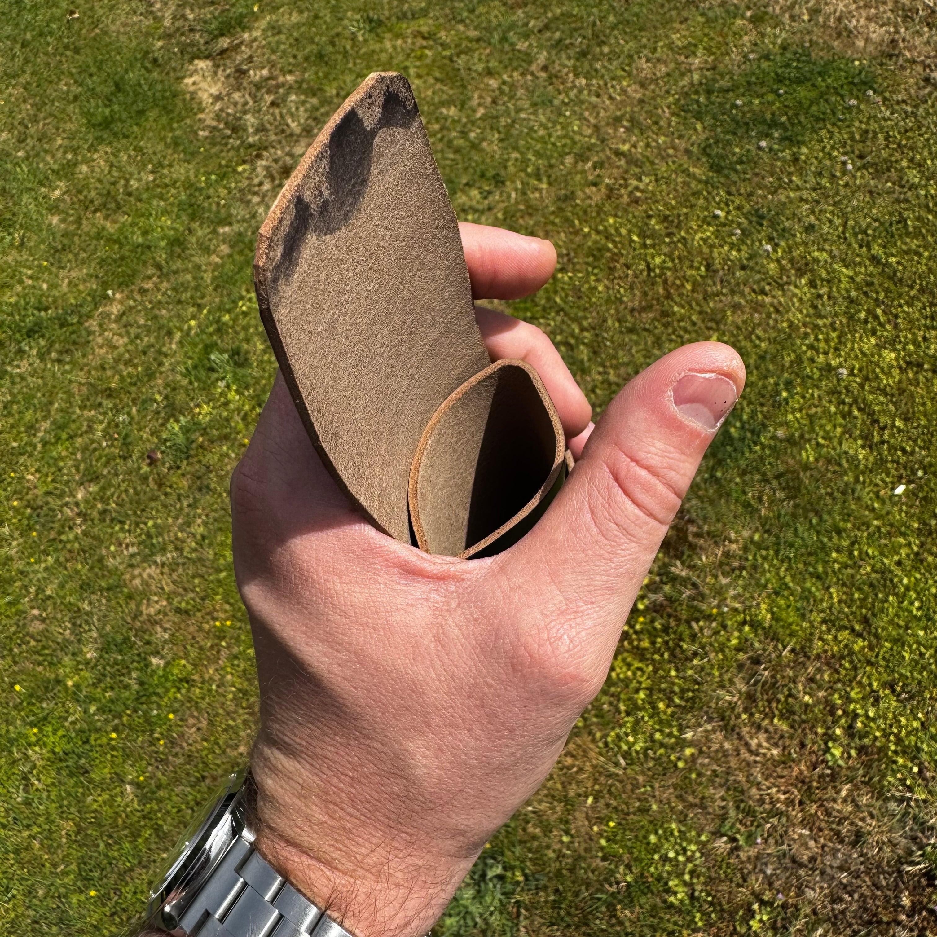 Top-down view of the open black No. 66 Woodsman leather fold wallet held in hand outdoors.