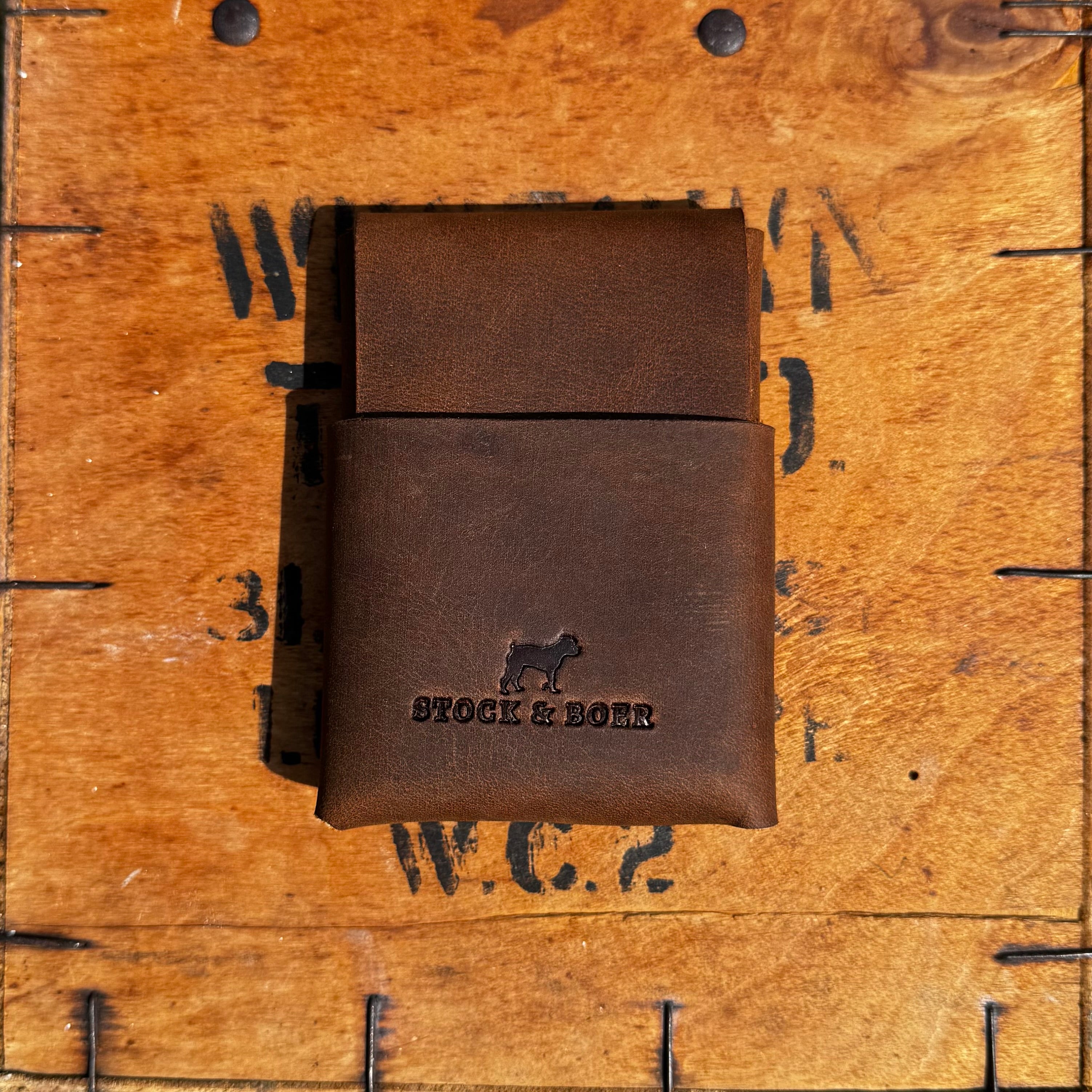 Closed front view of the No. 66 Woodsman leather fold wallet in Crazy Horse, resting on a vintage stamped wooden crate.