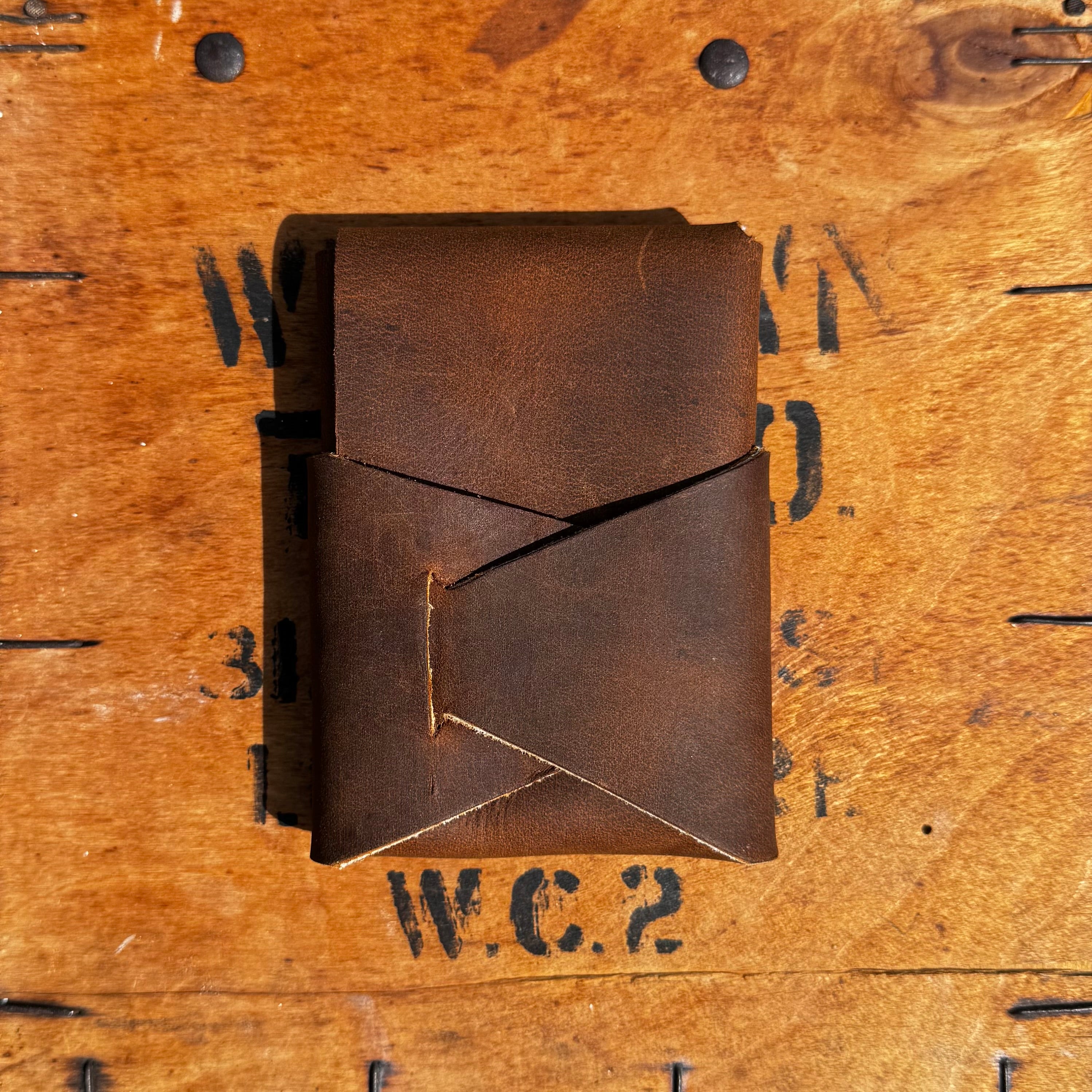 Flat lay of the No. 66 Woodsman leather fold wallet in Crazy Horse, displayed on a rustic wooden crate background.