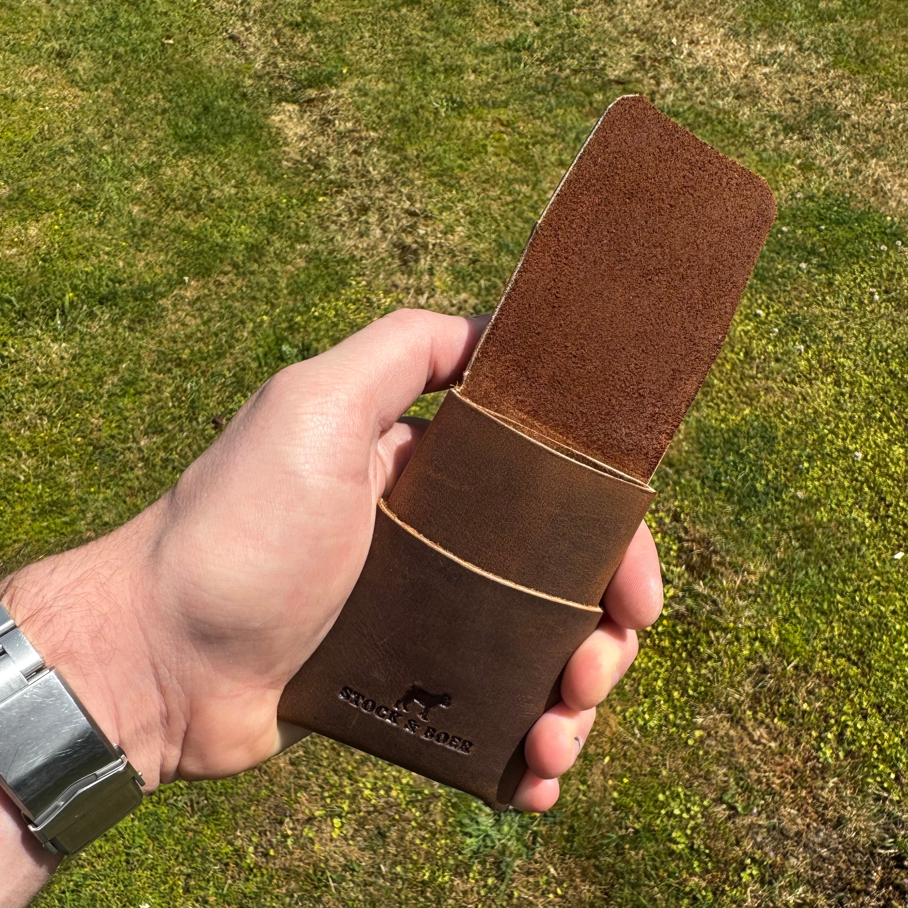 Handheld view of the open No. 66 Woodsman leather fold wallet in Crazy Horse, showcasing the rugged interior leather texture outdoors.