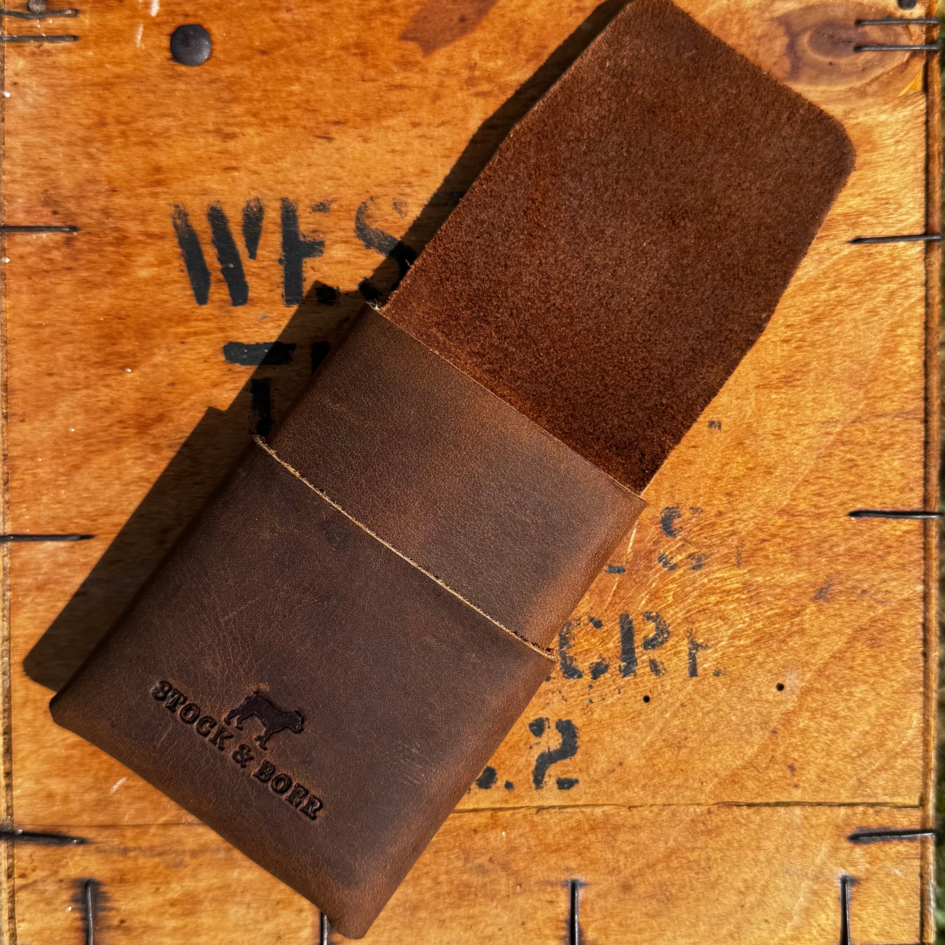 Partially open view showing the interior design of the No. 66 Woodsman leather fold wallet, handcrafted from Crazy Horse leather on a vintage crate.