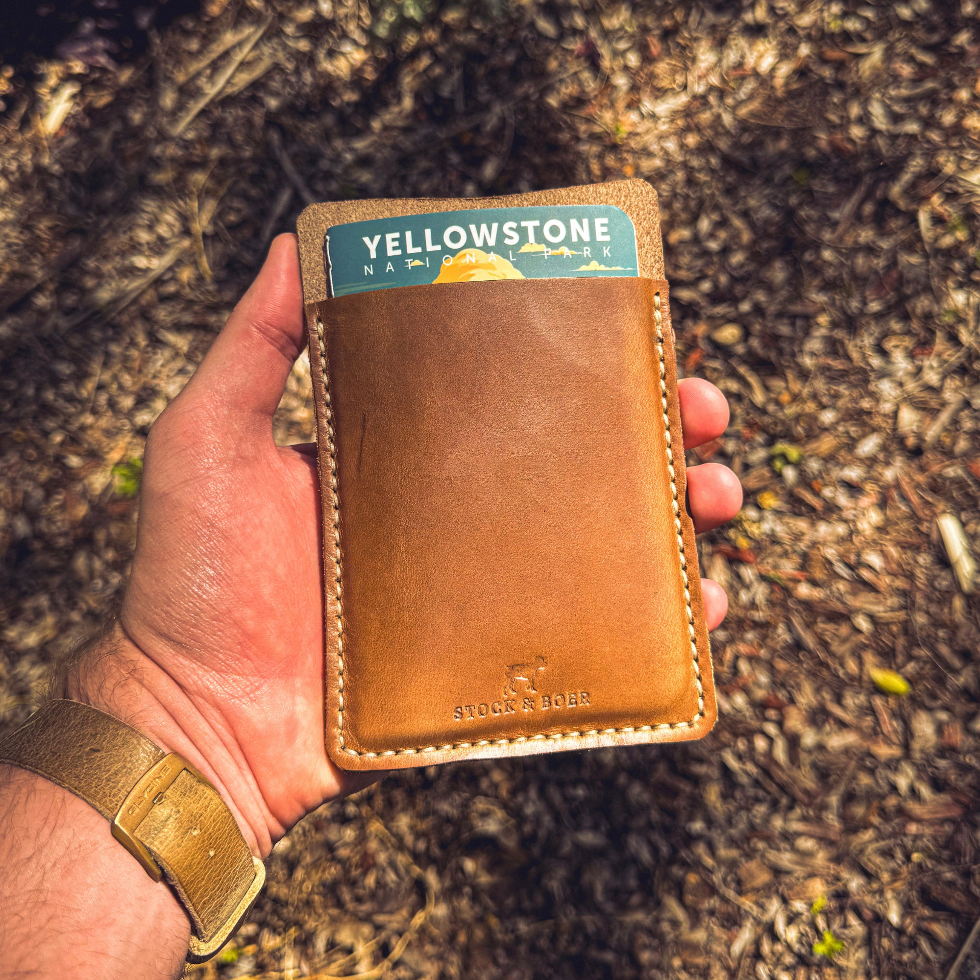 Close-up of a No. 9 Ledger leather EDC pouch held in hand, featuring a Yellowstone National Park notebook inserted.