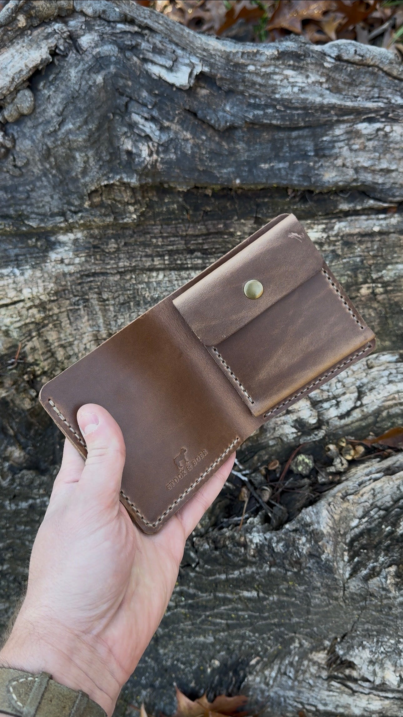 A video showcasing a hand holding the closed No. 3 Pioneer Billfold Coin Wallet crafted from Natural Horween Chromexcel leather.  A product demonstration video set against a rugged tree bark background.
