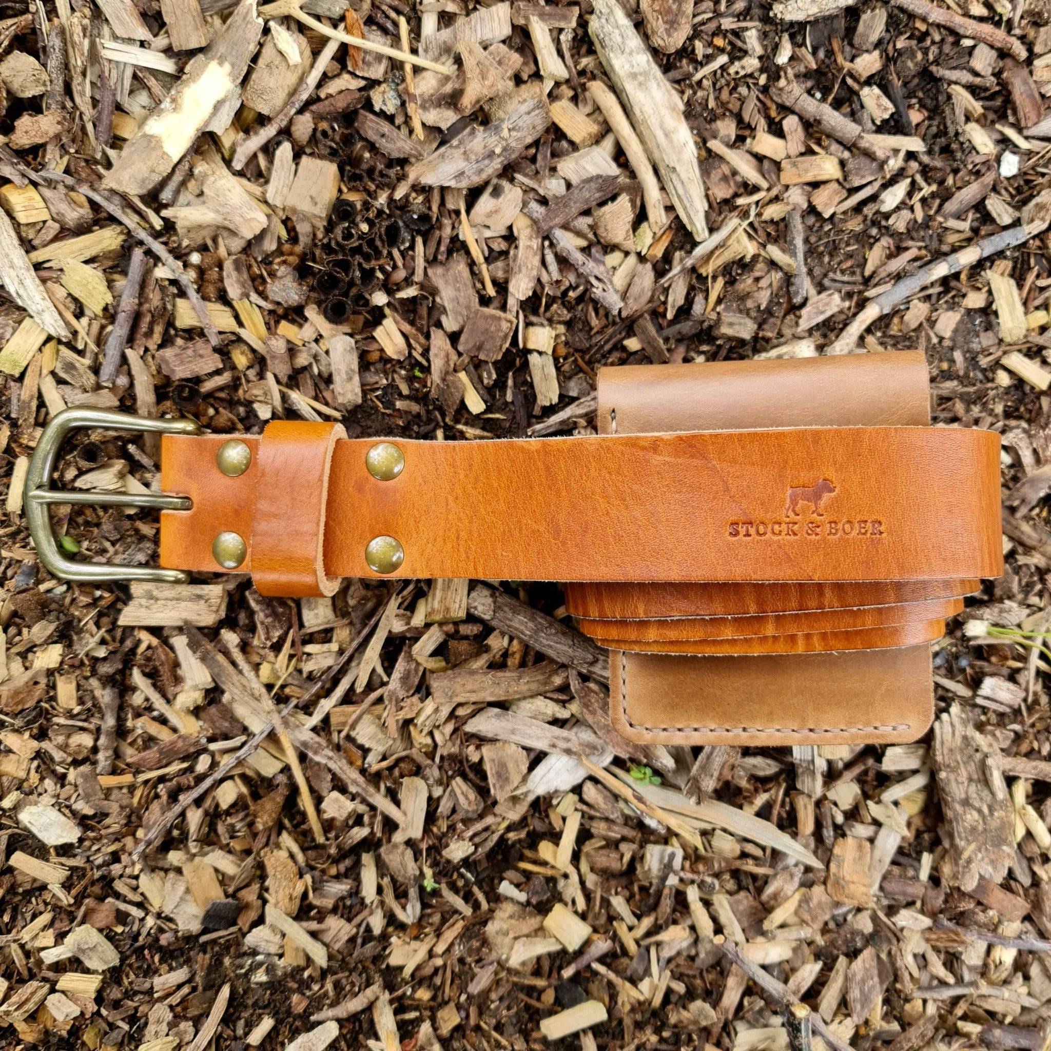 Top view of the Horween English Tan Dublin belt and wallet bundle stamped with the Stock & Boer logo on wood chips.