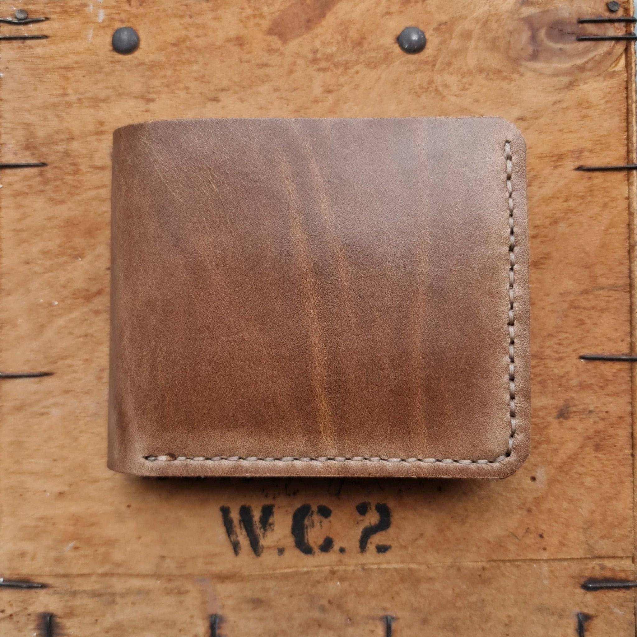 A closed Horween Natural Chromexcel leather wallet resting on a vintage wooden crate.