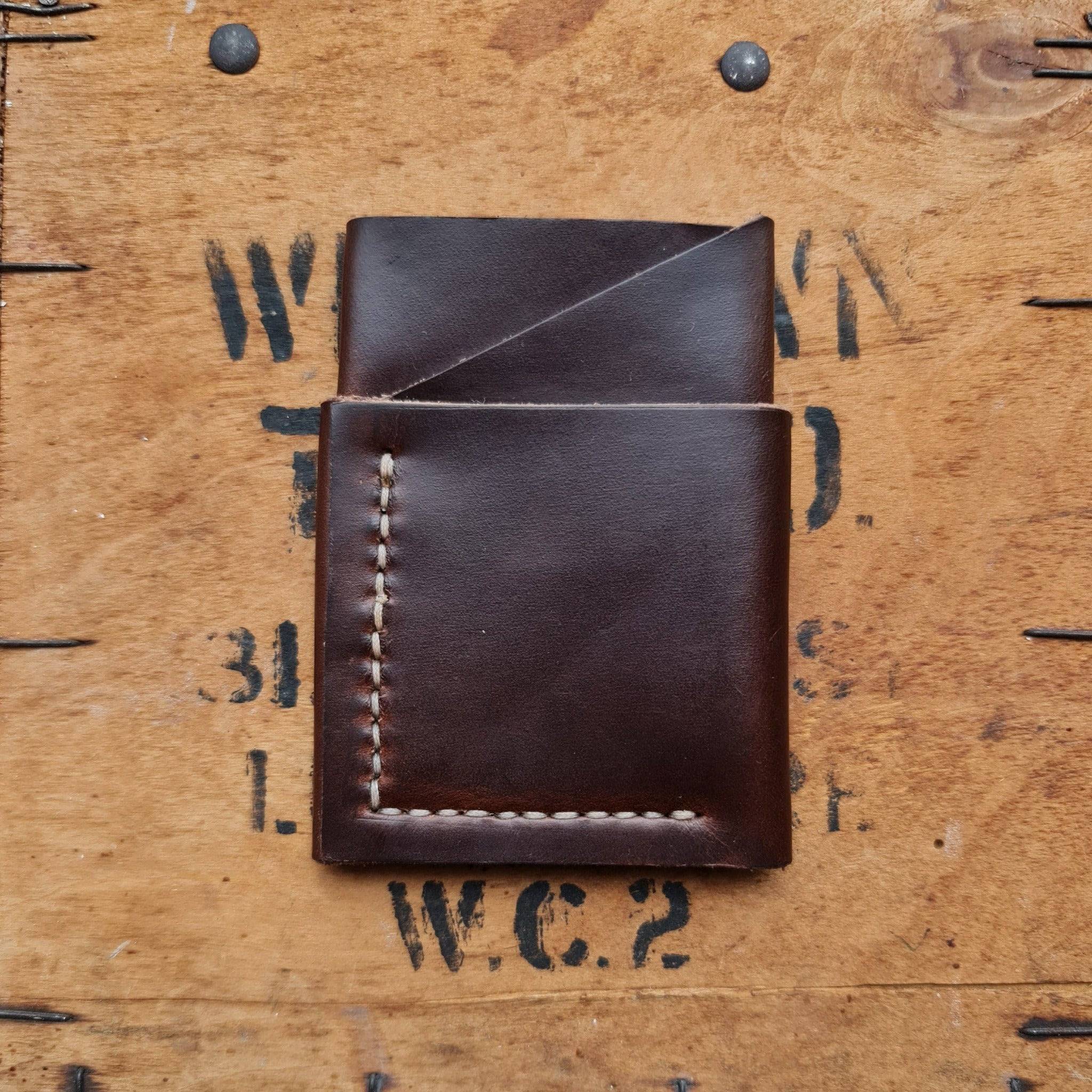  The No. 1835 TREKKER Front Pocket Wallet, crafted from brown Horween Chromexcel leather, resting on a vintage wooden surface. The image showcases the wallet's angled pocket design, precise hand-stitching, and rich, smooth finish of the brown Chromexcel leather.