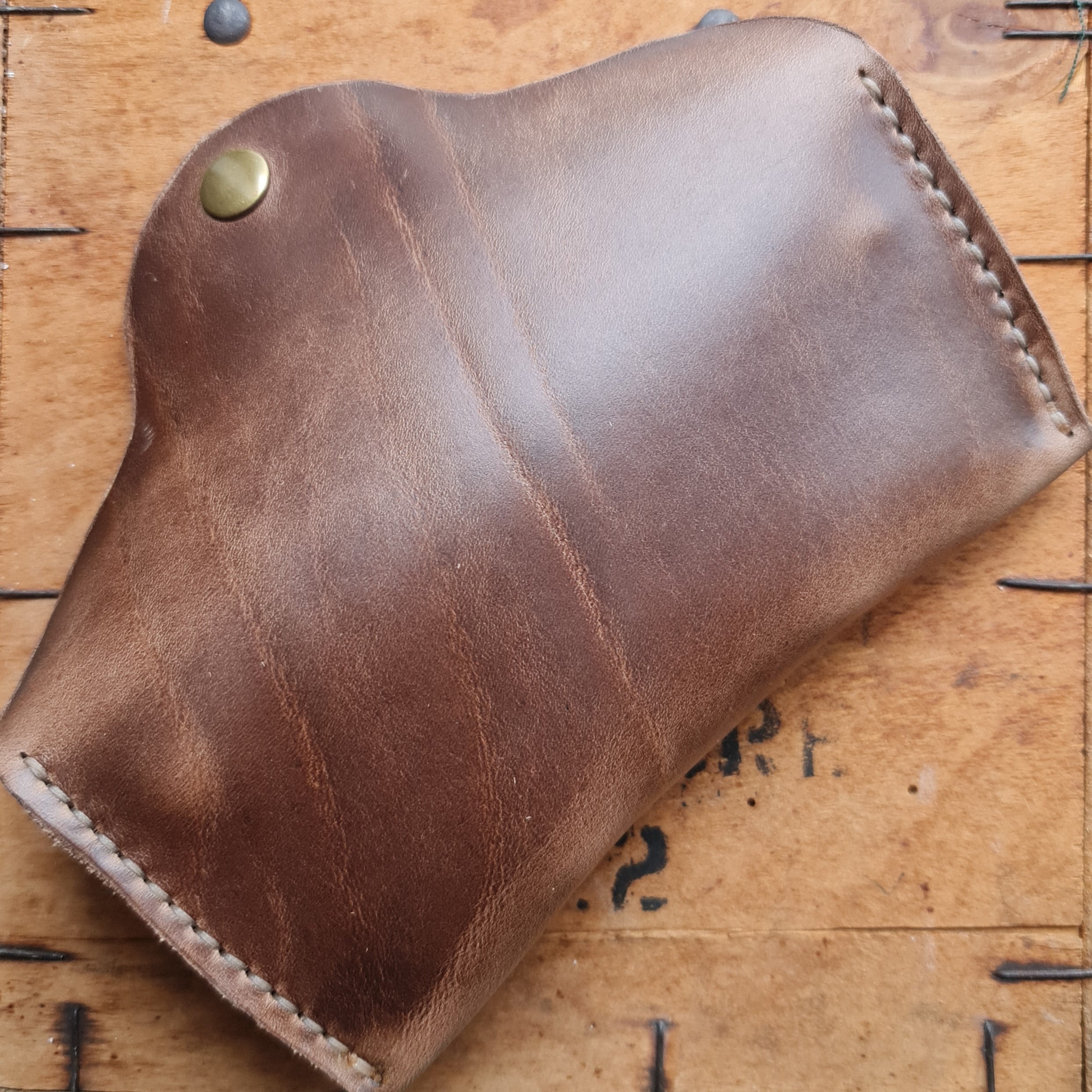 A closed brown No. 7 DESPERADO Sunglass Case placed on top of a wooden crate surface.