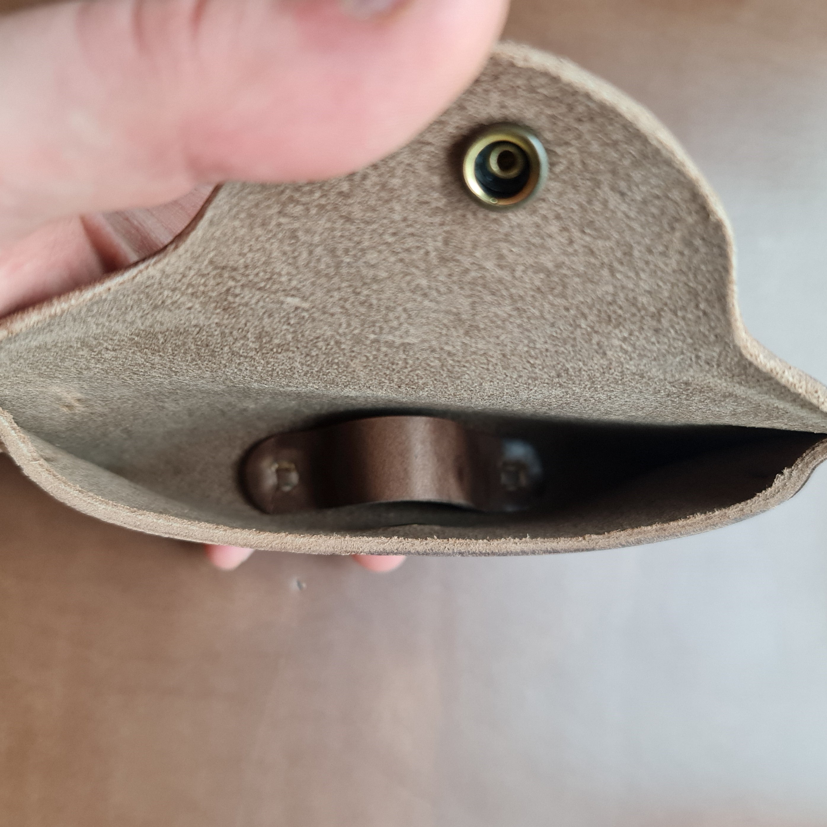 A close-up view of the interior of a No. 7 DESPERADO Sunglass Case, held by a hand, showing the internal leather nose bridge support.